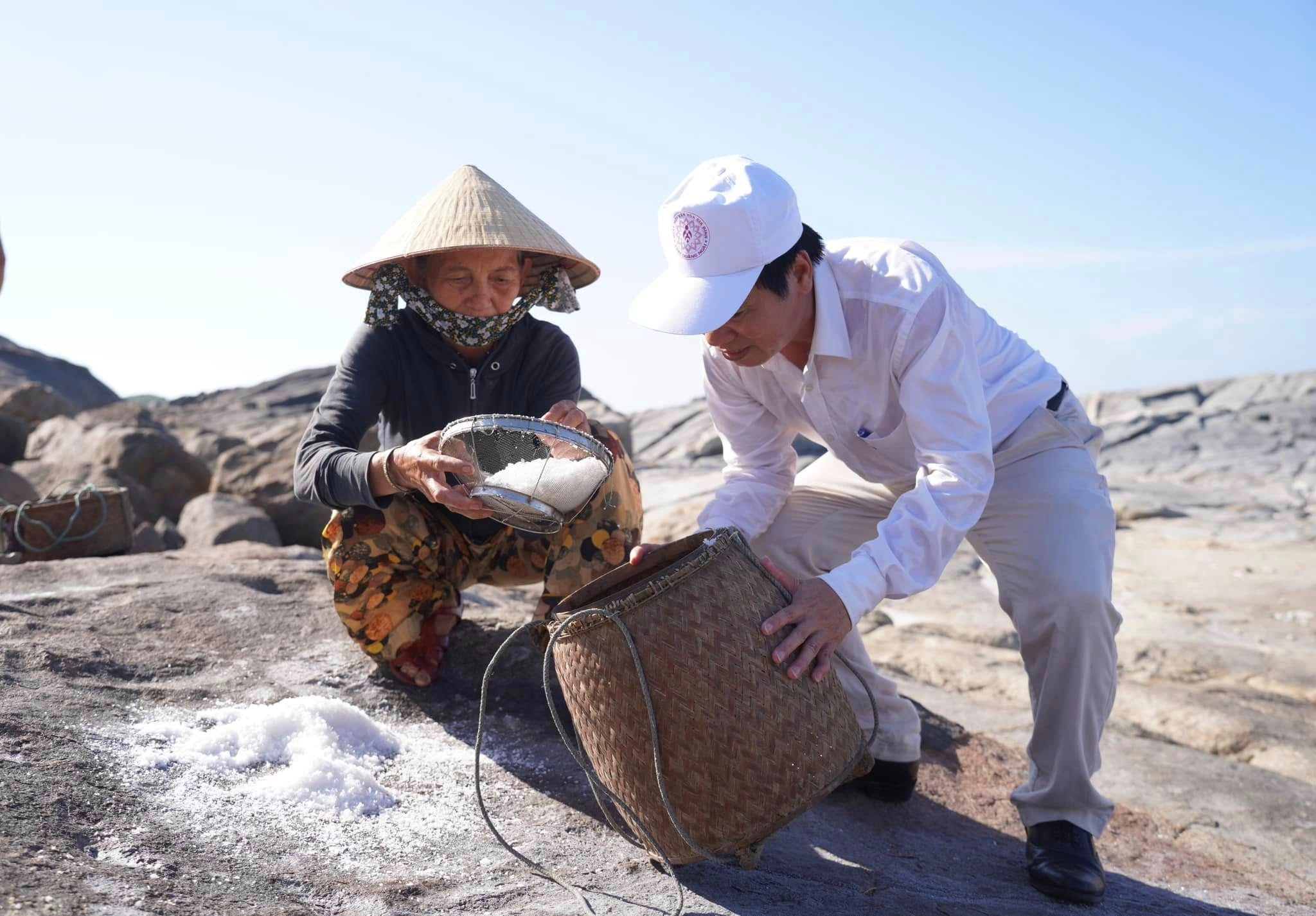 Bà Vân thuyết minh với du khách về cách làm muối trên gành đá đã được duy trì suốt ngàn năm. Ảnh H.G