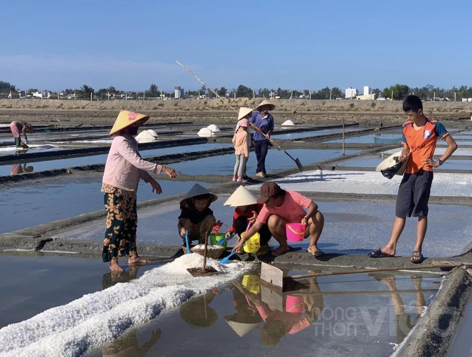 Các em nhỏ học thu hoạch muối trên đồng muối Sa Huỳnh. Ảnh M.T