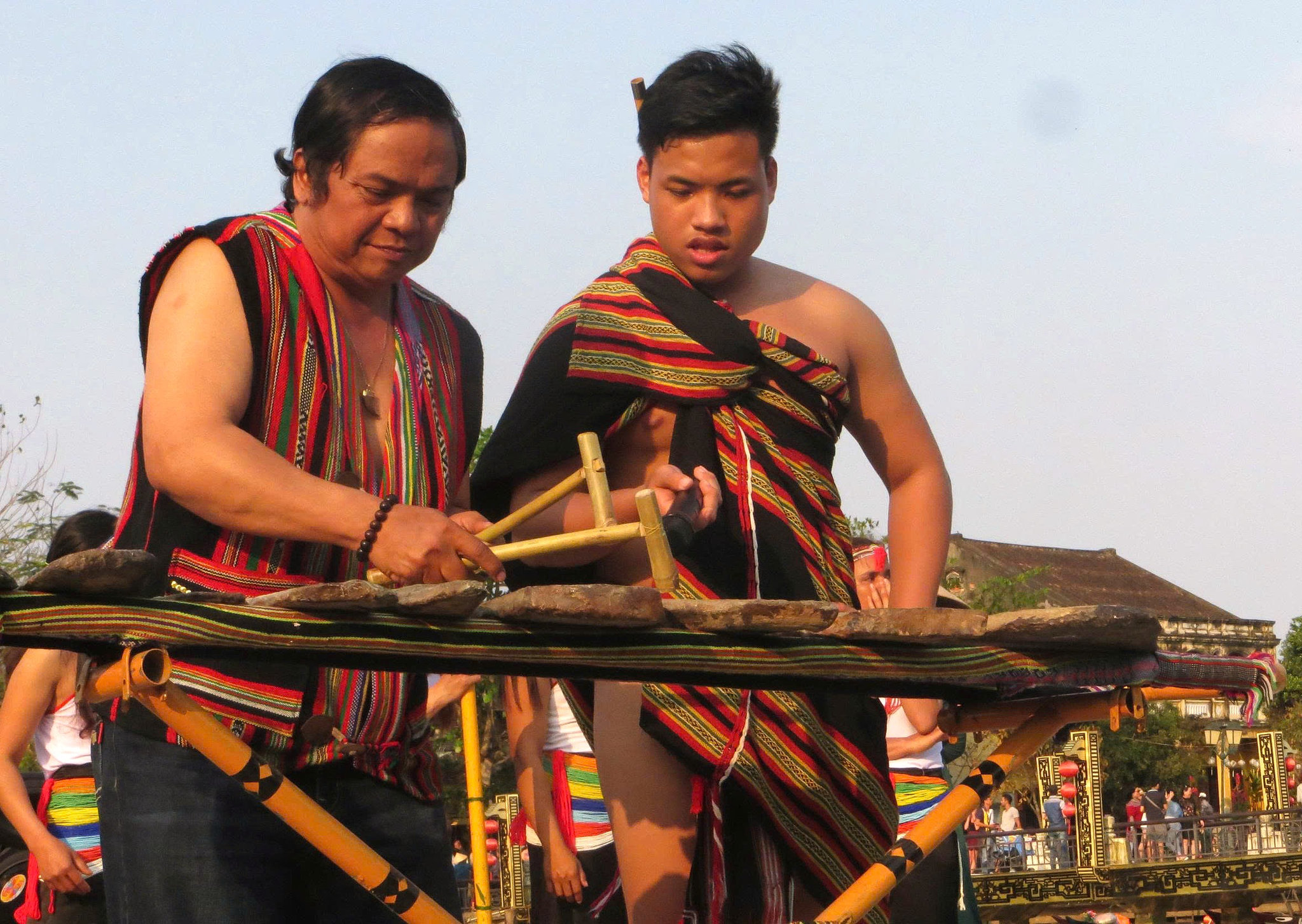 Cố nhạc sĩ Dương Trinh (người đánh đàn đá) biểu diễn tại phố cổ Hội An trong trang phục truyền thống vùng cao do anh Trần Quang thiết kế, may đo. Ảnh: CẨM LAI.