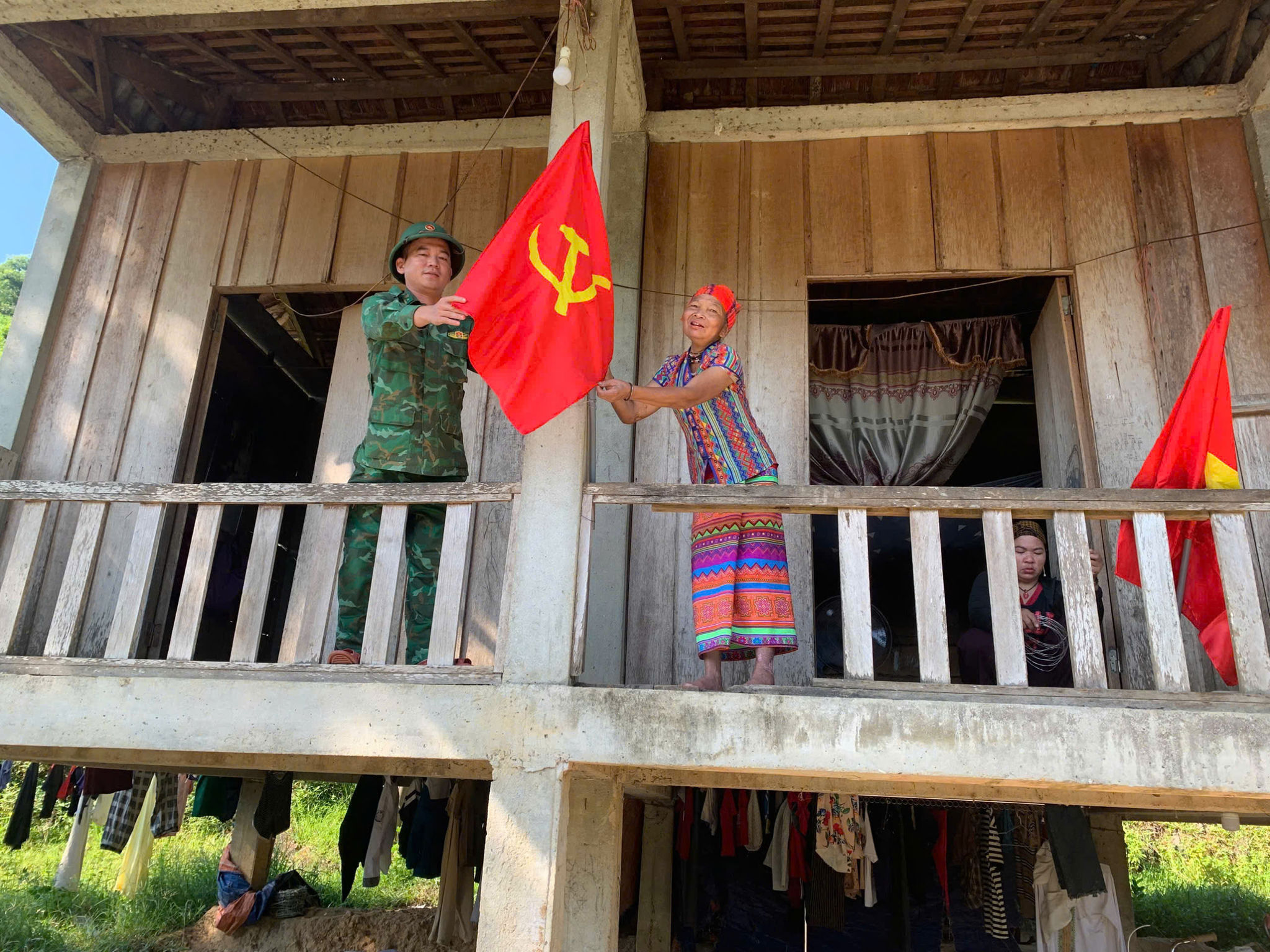 Thiếu Tá Đoàn Văn Tiệp – Tổ trưởng tổ cắm bản Rào Tre hỗ trợ bà treo cờ Tổ quốc.