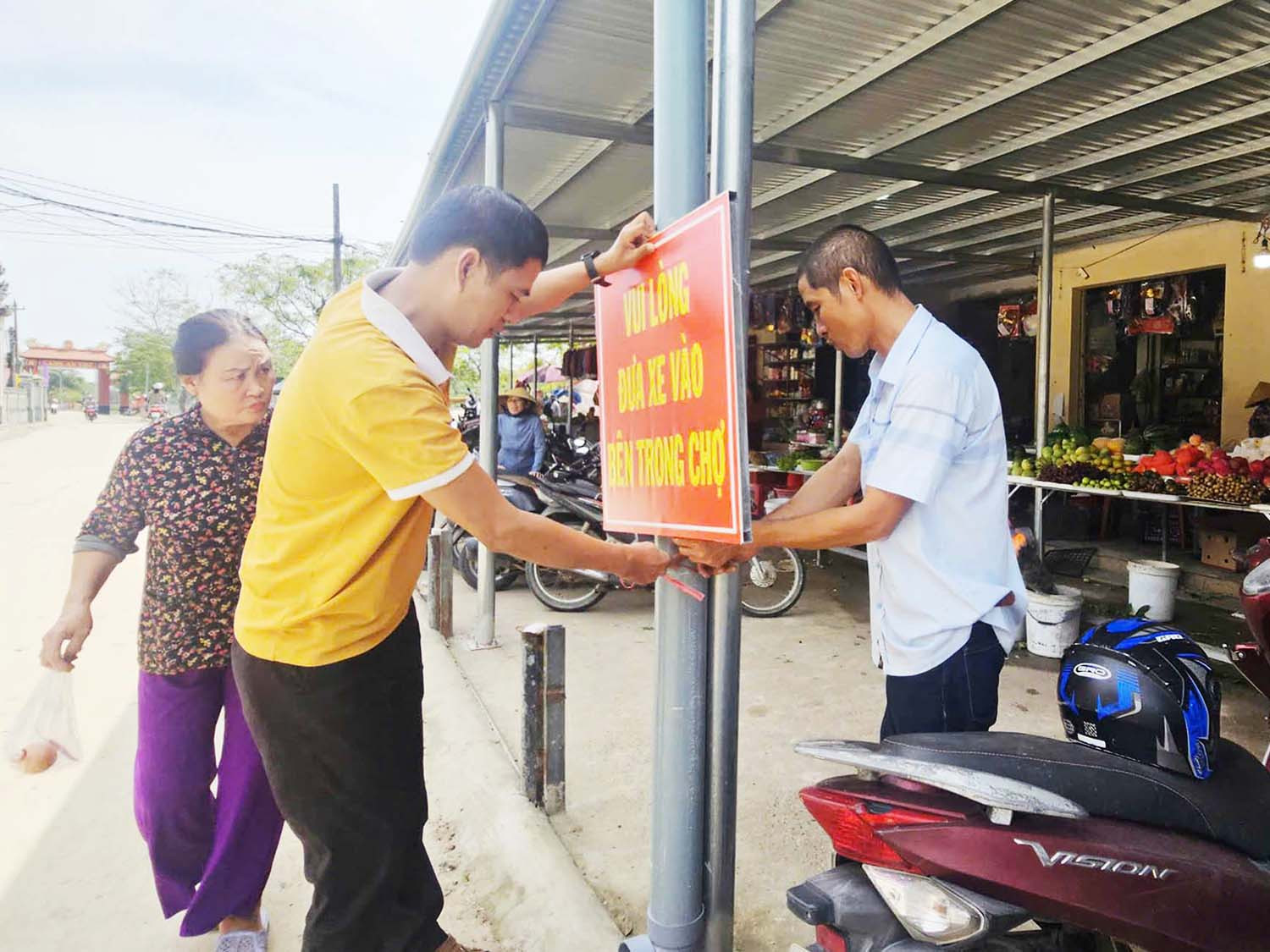 Trưởng thôn Nguyễn Như Khoa (trái) cùng bà con treo biển nhắc nhở mọi người trước chợ Hải Hòa. Ảnh: T.Phùng