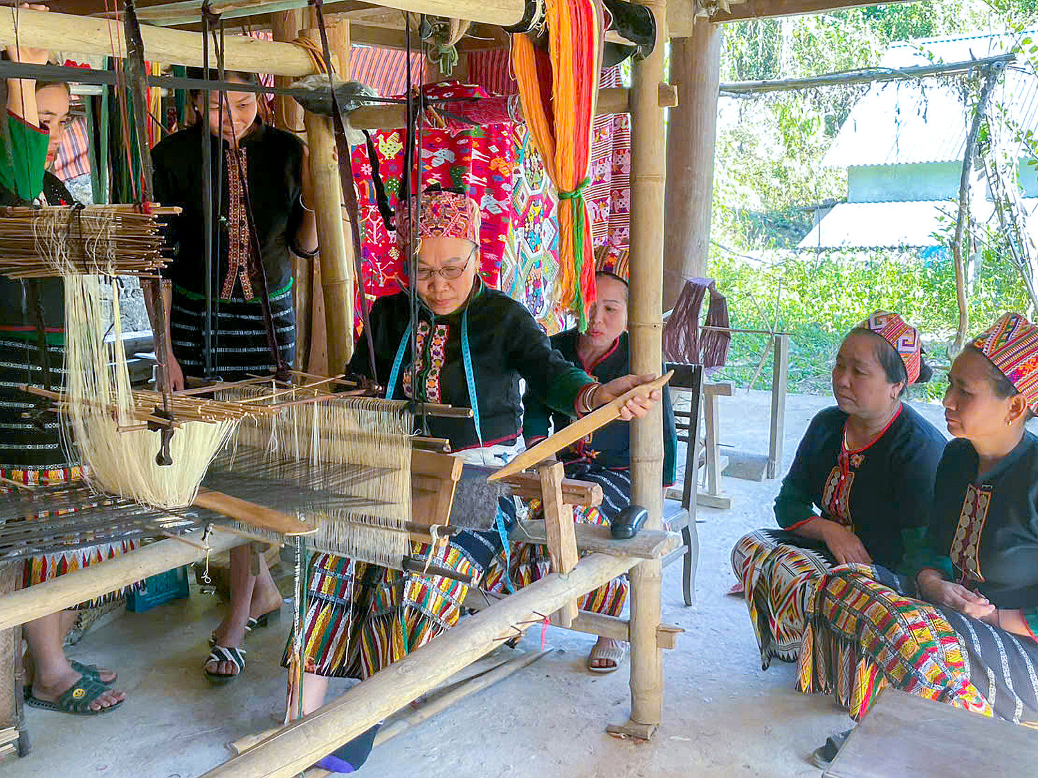 Phụ nữ bản Hữu Lập quây quần bên khung cửi, trao đổi kinh nghiệm dệt thổ cẩm.